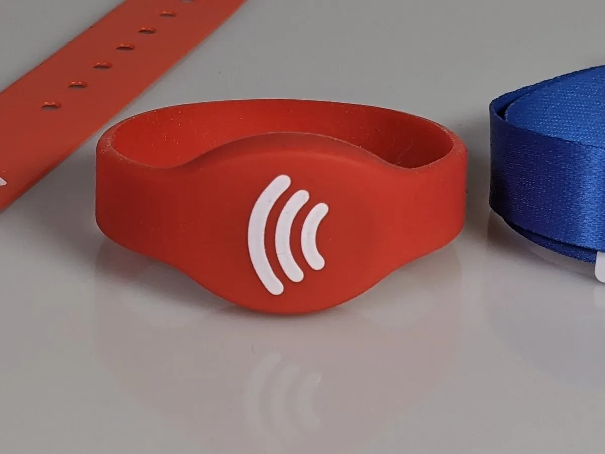 A red silicone FunFangle wristband with the tap mark on its face