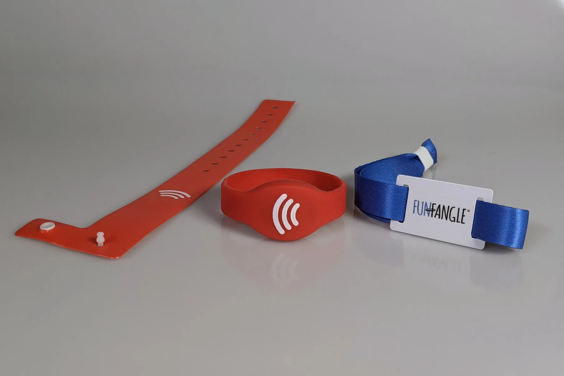 The three FunFangle wristband styles side by side: a snap-closure vinyl band, a silicone band, and a stretch fabric band